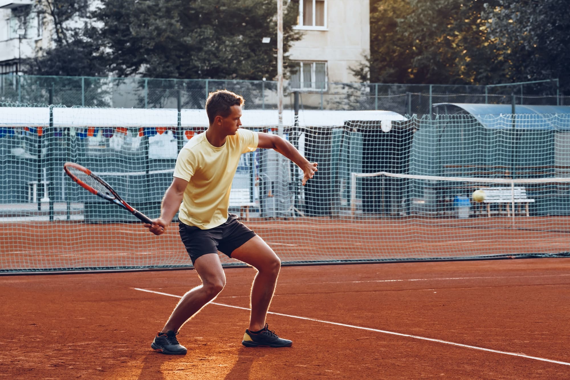 Young handsome man playing tennis on the tennis court